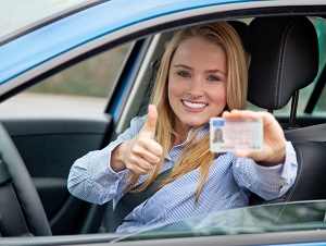 female driver holding up drivers license